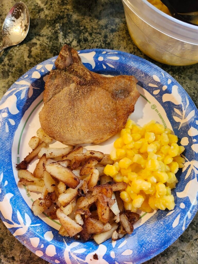 Porkchops with garlic and onion powder baked, fried potatoes, and hominy